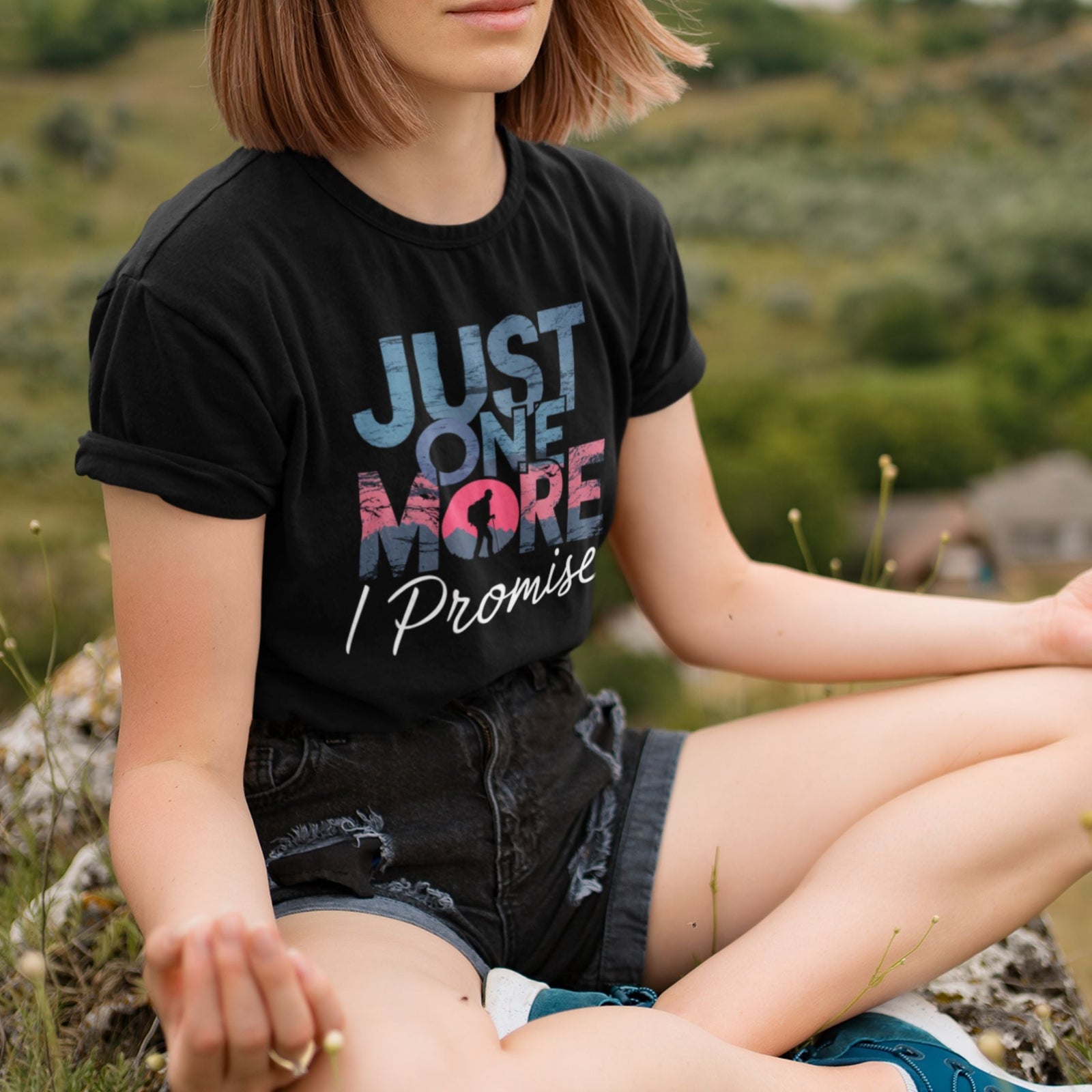 A woman wearing a trendy black t-shirt with the phrase 'Just One More I Promise' enjoying nature, showcasing style trendy t-shirts.
