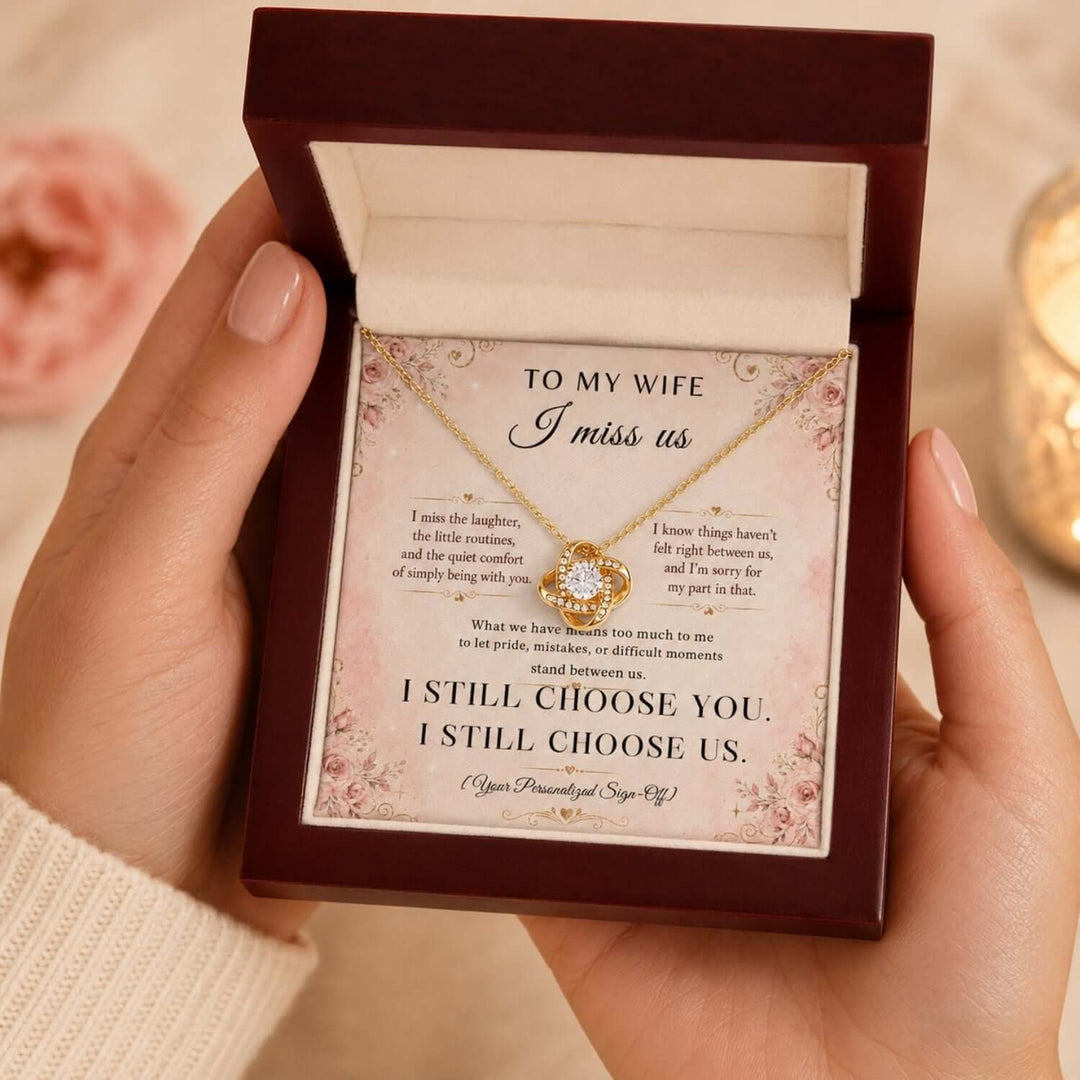 A woman holding a necklace in a gift box with a heartfelt message card for a wife apology necklace.