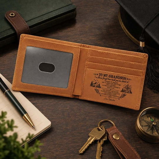 Engraved wallet for grandson featuring a personalized message, placed on a wooden surface with stationery and compass.