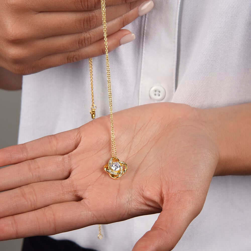 Meaningful daughter graduation or birthday gift, showcasing a gold Love Knot necklace held in a woman's hand.