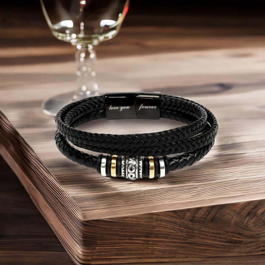 Grandson braided leather keepsake graduation milestone gift displayed on a wooden table with a glass in the background.