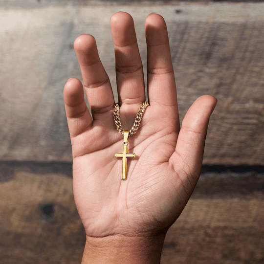 Gold personalized cross keepsake graduation held in hand, symbolizing love and strength as a milestone gift.